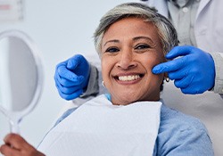 Woman smiling while holding small mirror
