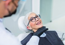 Woman with black glasses smiling at dentist