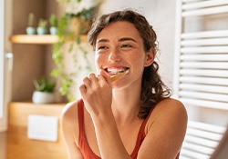 Woman smiling while brushing her teeth