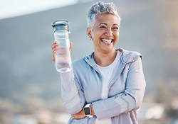 Woman smiling with water bottle on hike outside