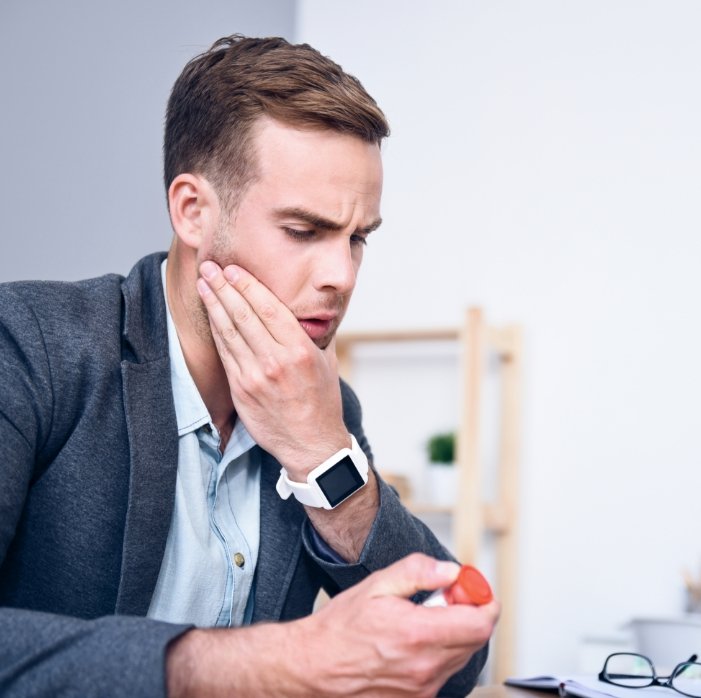 Man in need of emergency dentistry holding jaw in pain