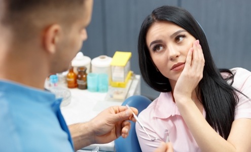 Woman in need of emergency dentistry holding cheek