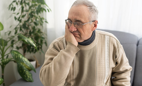 Man sitting on the couch rubbing his jaw in pain