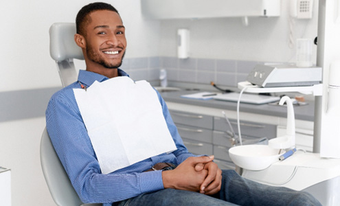 Man sitting in dental chair with hands folded