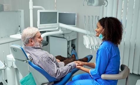 Senior dental patient talking with dental team member