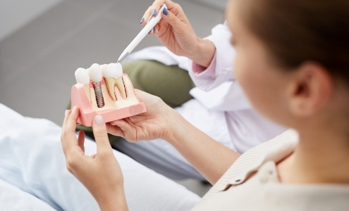 Dentist and patient looking at dental implant model together