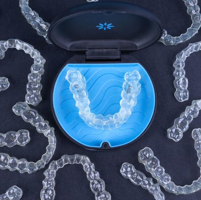 Sets of Invisalign aligners surrounding a carrying case