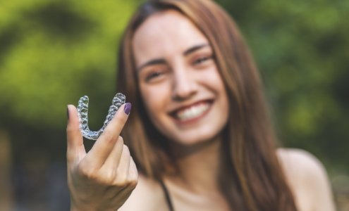 Smiling woman holding up an Invisalign tray