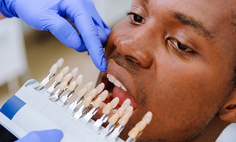 A dentist using a shade guide to check a patient’s enamel color
