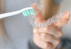 Person using soft brush to clean Invisalign tray