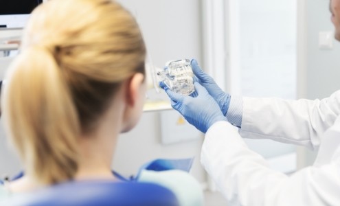 Dentist and patient looking at smile model during dental checkup and teeth cleaning visit