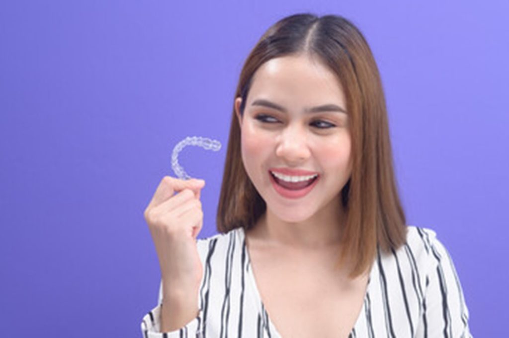 Woman holding her Invisalign tray.