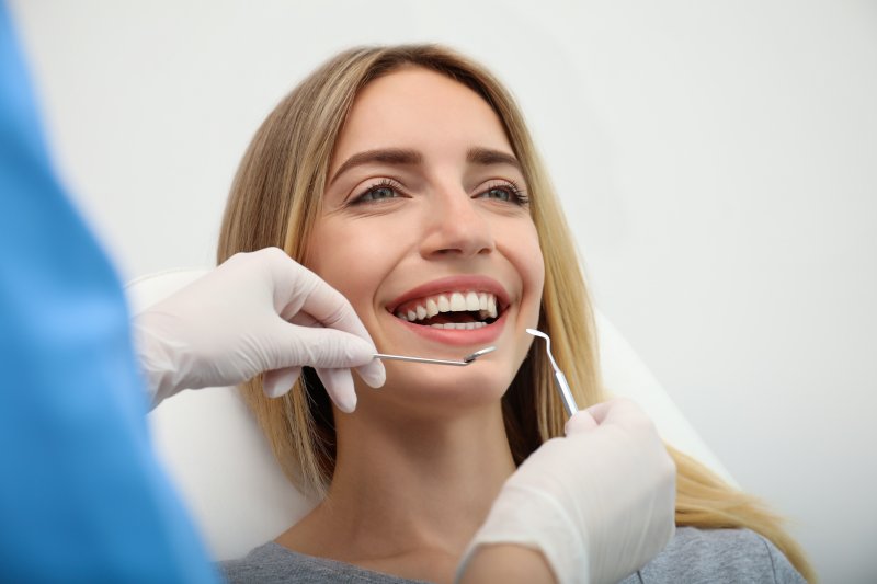 A blonde, smiling woman receiving care from her cosmetic dentist